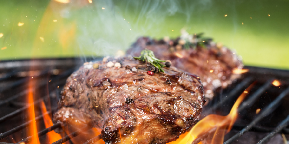 Beef cooking on a flaming grill